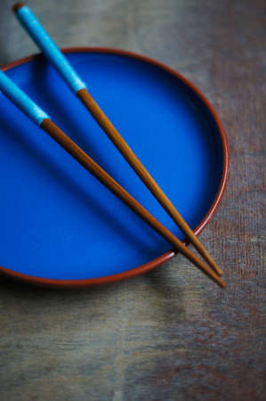 Blue plate with chopsticks on the wooden tableの写真素材