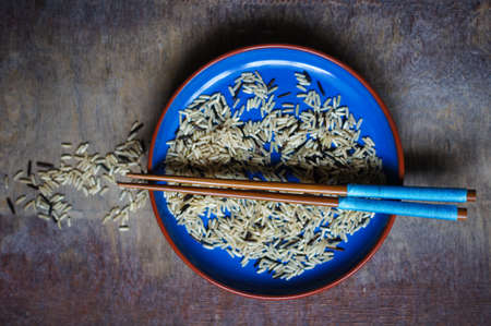 bowl of rice with wooden chopsticks and a wood place matの写真素材