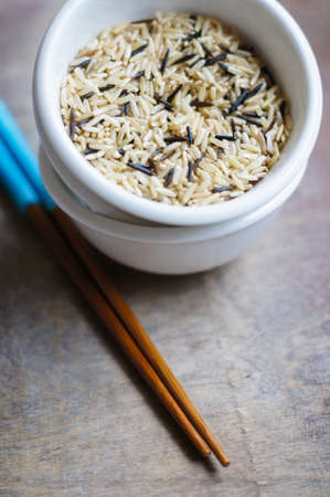 bowl of rice with wooden chopsticks and a wood place mat