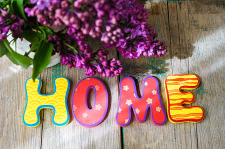 Lilac flowers in a pot and HOME letters on the wooden tableの写真素材