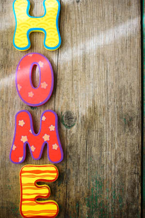 Home in colorful letters, in light white interior, on wooden shelfの写真素材