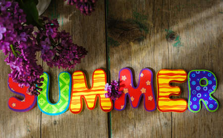 Lilac flowers in a pot and summer word on the wooden tableの写真素材