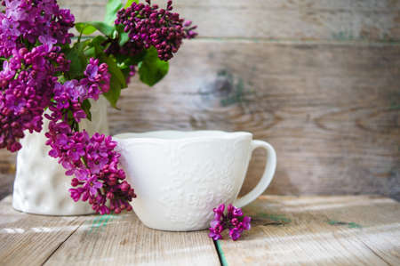 Lilac flowers in a pot and cup of tea in rustic interiorの写真素材