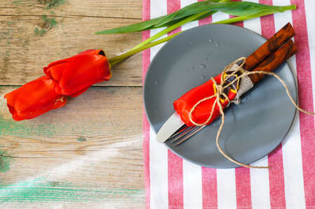 Red tulips with table set on a napkins, rustic
