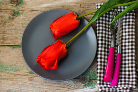 Red tulips with table set on a napkins, rustic
