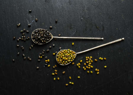 Different types of beans in the vintage spoons on the black stone backgroundの写真素材