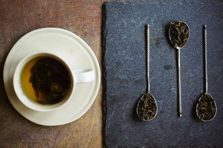 Green tea in vintage spoons on the black stone boardの写真素材
