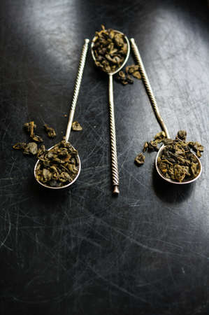Green tea in vintage spoons on the black stone boardの写真素材