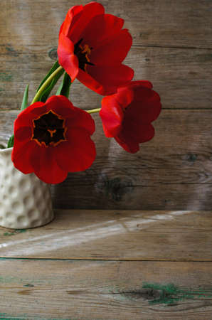 Red tulips on the old wooden tableの写真素材