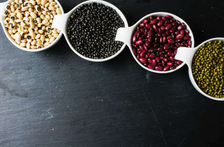 Four types of dry beans  on the black stone backgroudの写真素材