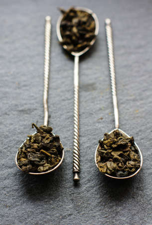Green tea in vintage spoons on the black stone boardの写真素材