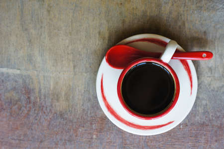 Cup of coffee with red sticks on the old table in the morningの写真素材