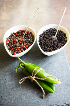 closeup green chilli peppers and different types of peppercornsの写真素材