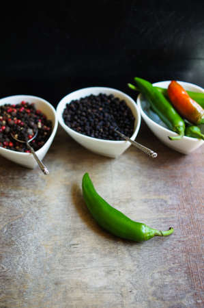 closeup green chilli peppers and different types of peppercornsの写真素材