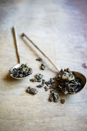 The leaves of green tea in vintage spoon on the old wooden backgroundの写真素材