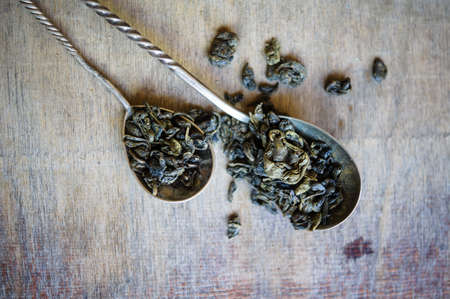 The leaves of green tea in vintage spoon on the old wooden backgroundの写真素材