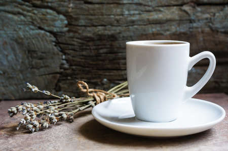 Cup of coffee and dried lavander flowers on the old wooden tableの写真素材