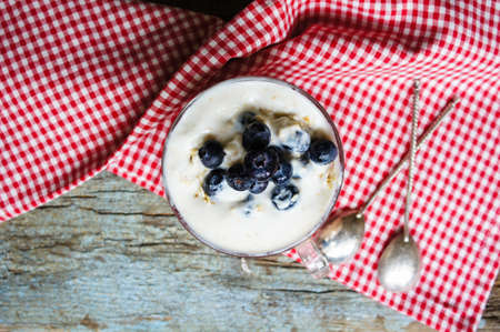 Oat flake and fresh blue berries in bowl with vintage spoon on rustic woodの写真素材