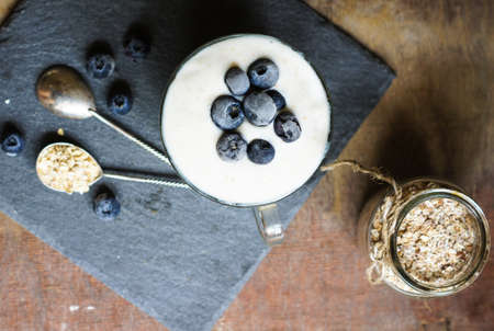 Oat flake and fresh blue berries in bowl with vintage spoon on rustic woodの写真素材