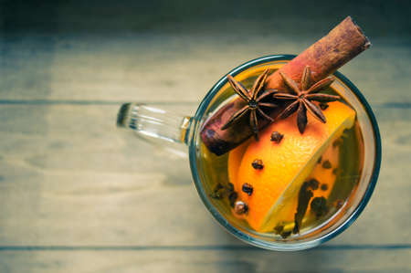 Glass with hot spiced wine with orange fruit, scarf and snowの写真素材