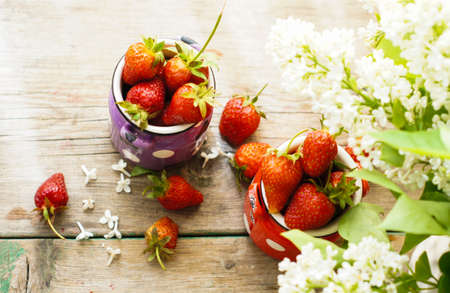Fresh strawberries and white lilac flowers on the old wooden tableの写真素材