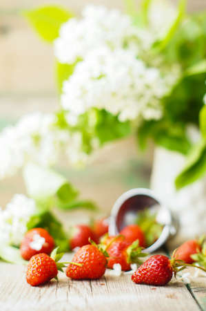 Fresh strawberries and white lilac flowers on the old wooden tableの写真素材