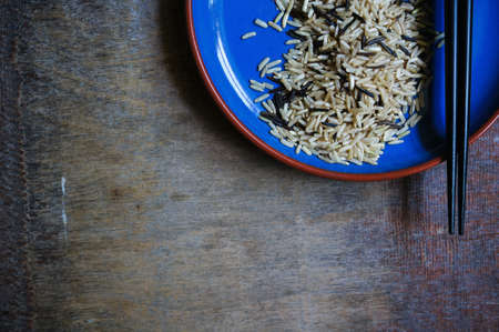 wild rice in ceramic bowl and chopsicks on wooden backgroundの写真素材