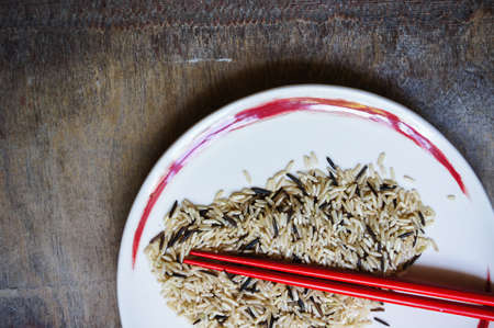 wild rice in ceramic bowl and chopsicks on wooden backgroundの写真素材