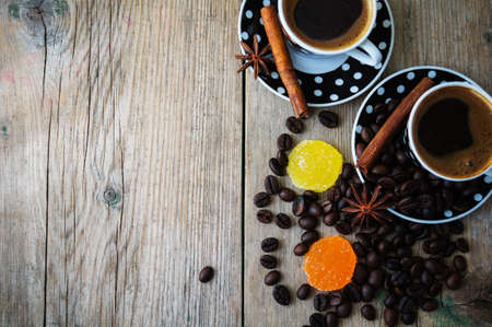 Black and white dots cup of coffee on the old wooden table with coffee beans, cinnamon sticks and anise starの写真素材