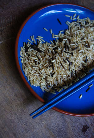 wild rice in ceramic bowl and chopsicks on wooden backgroundの写真素材
