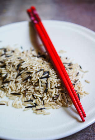 wild rice in ceramic bowl and chopsicks on wooden backgroundの写真素材