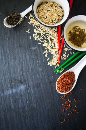 Tea and rice in the bowls with colorful chopsticks on the rustic tableの写真素材
