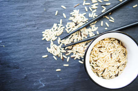 wild rice in ceramic bowl and chopsticks on wooden backgroundの写真素材