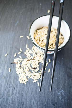 wild rice in ceramic bowl and chopsticks on wooden backgroundの写真素材