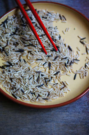 wild rice in ceramic bowl and chopsicks on wooden backgroundの写真素材