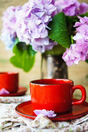 Hydrangea flowers in a vase and cup of coffee on the wooden table