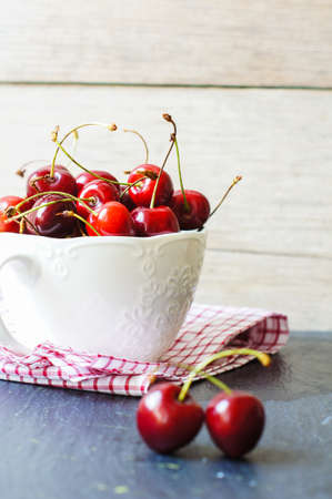ripe sweet cherries in a bowl on a bright napkinの写真素材