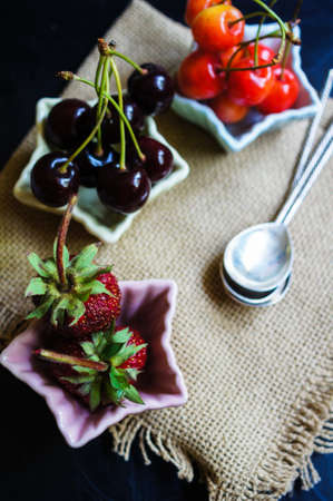 Three star-shaped bowls with fresh seasonal fruits - strawberry and two types of cherriesの写真素材