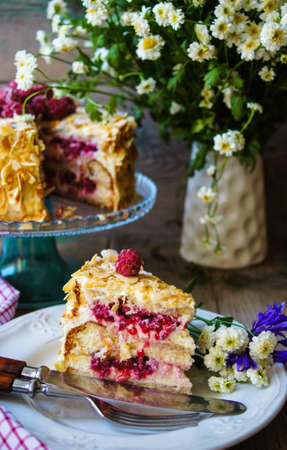 almond cake with Raspberries on the plate and summertime flowersの写真素材
