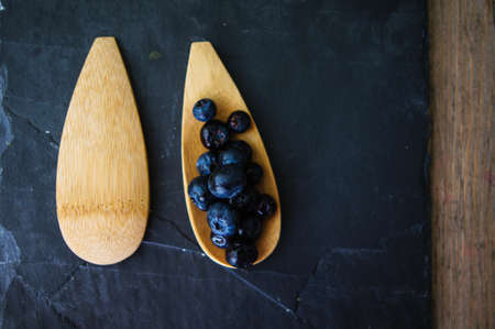 Fresh blueberries in vintage bowl and bright napkin on old wooden tableの写真素材