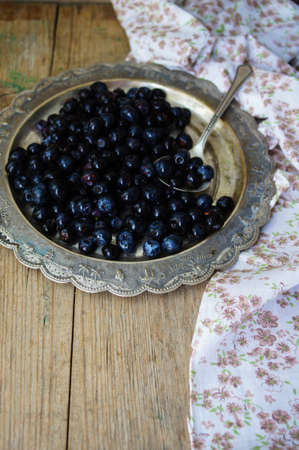 Fresh blueberries in vintage bowl and bright napkin on old wooden tableの写真素材
