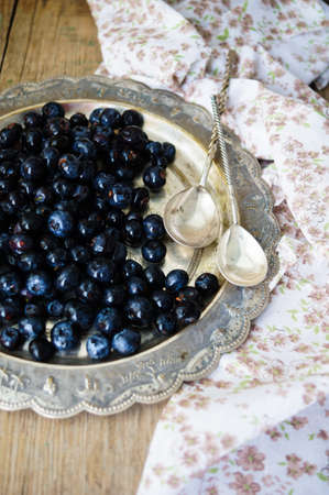 Fresh blueberries in vintage bowl and bright napkin on old wooden tableの写真素材