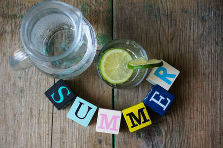 Water with lime and word summer on the wooden 