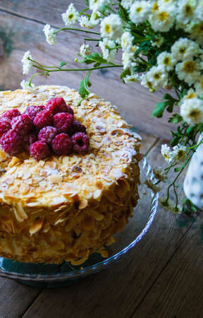 Almond cake with Raspberries on the plate and summertime flowersの写真素材