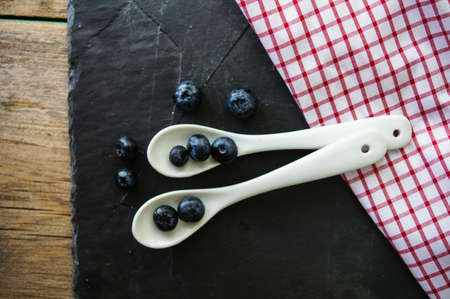 Fresh blueberries in vintage bowl and bright napkin on old wooden tableの写真素材