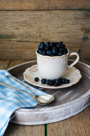 Fresh blueberries in vintage bowl and bright napkin on old wooden tableの写真素材