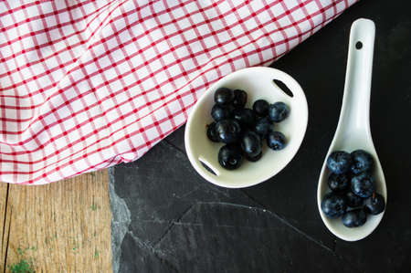 Fresh blueberries in vintage bowl and bright napkin on old wooden tableの写真素材