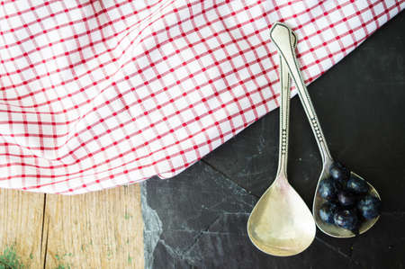 Fresh blueberries in vintage bowl and bright napkin on old wooden tableの写真素材
