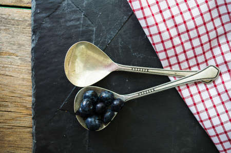 Fresh blueberries in vintage bowl and bright napkin on old wooden tableの写真素材