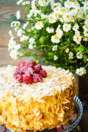 Almond cake with Raspberries on the plate and summertime flowersの写真素材